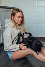pexels-photo-7788860 Young woman sitting indoors with her playful French bulldog, enjoying a calm moment.